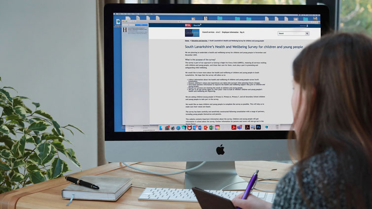 This image shows the back of someone looking at a screen displaying a page from the council's website