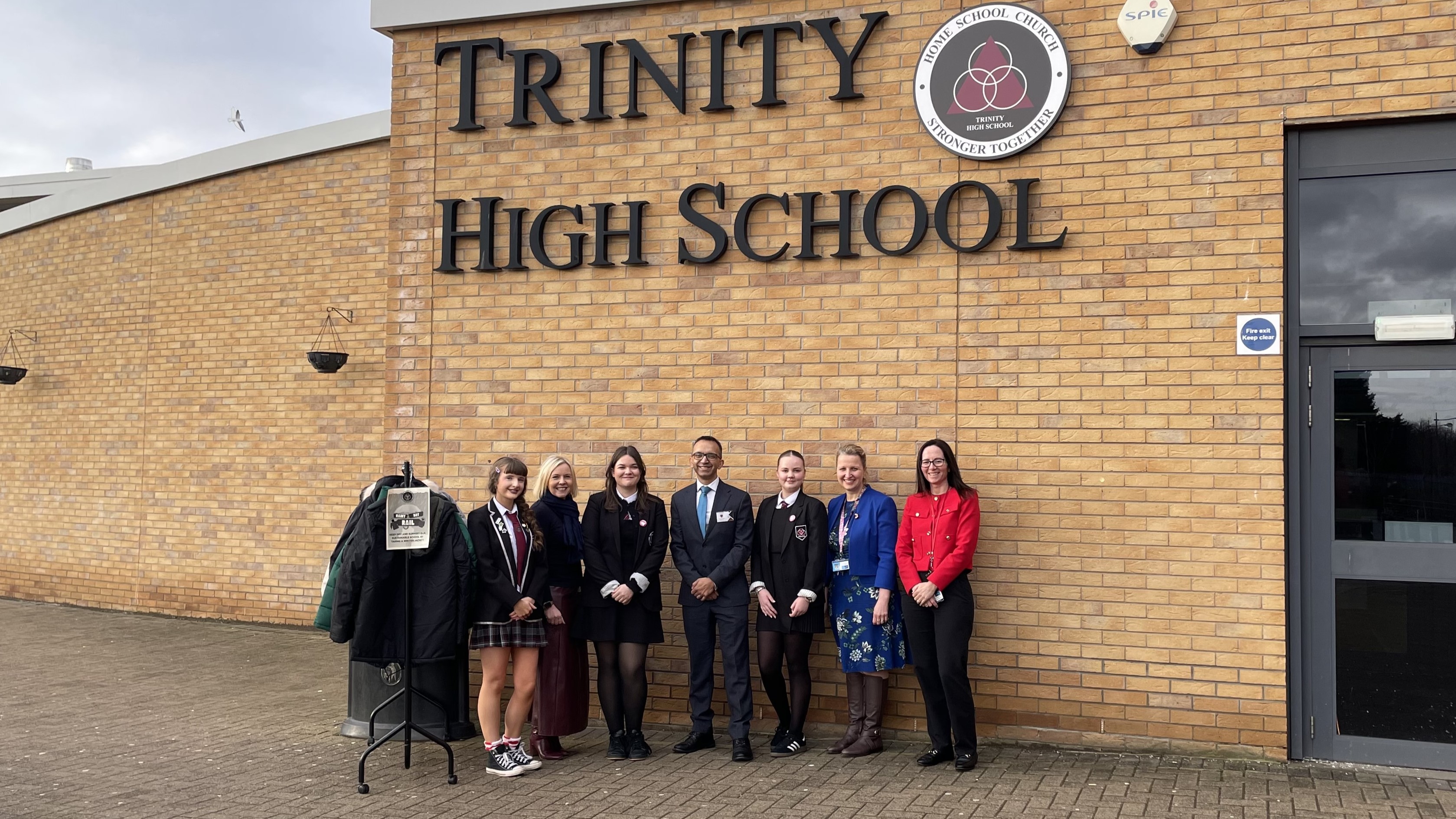 pupils and teaching staff outside school with winter jackets clothes rail