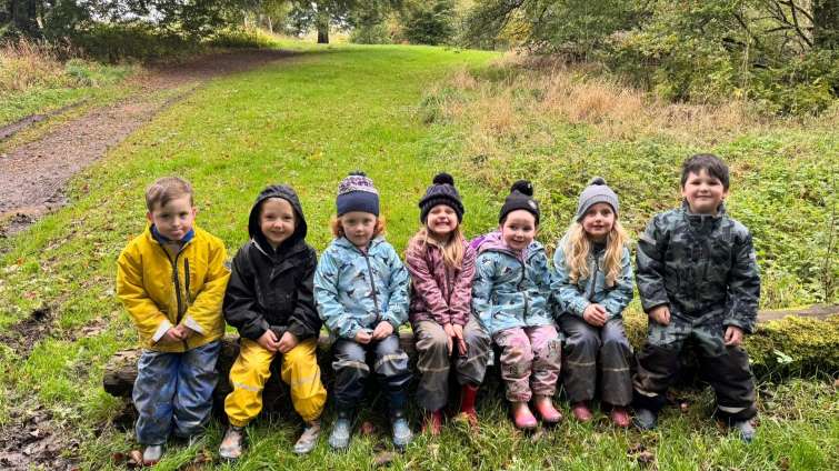 children sitting on a log in a woodland setting