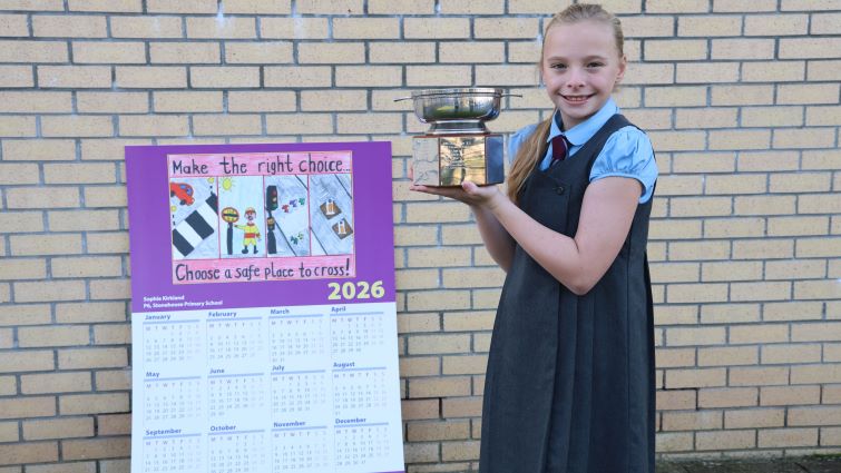 This image shows 2026 Road Safety Calendar Competition winner Sophie Anderson with her trophy and a large scale calendar